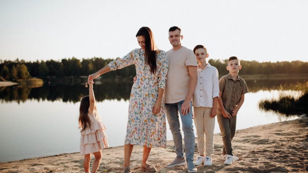 A family of five enjoys a serene lakeside vacation at sunset, capturing precious moments together.